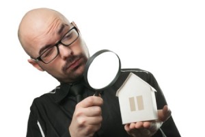 Man with a magnifying glass and paper house